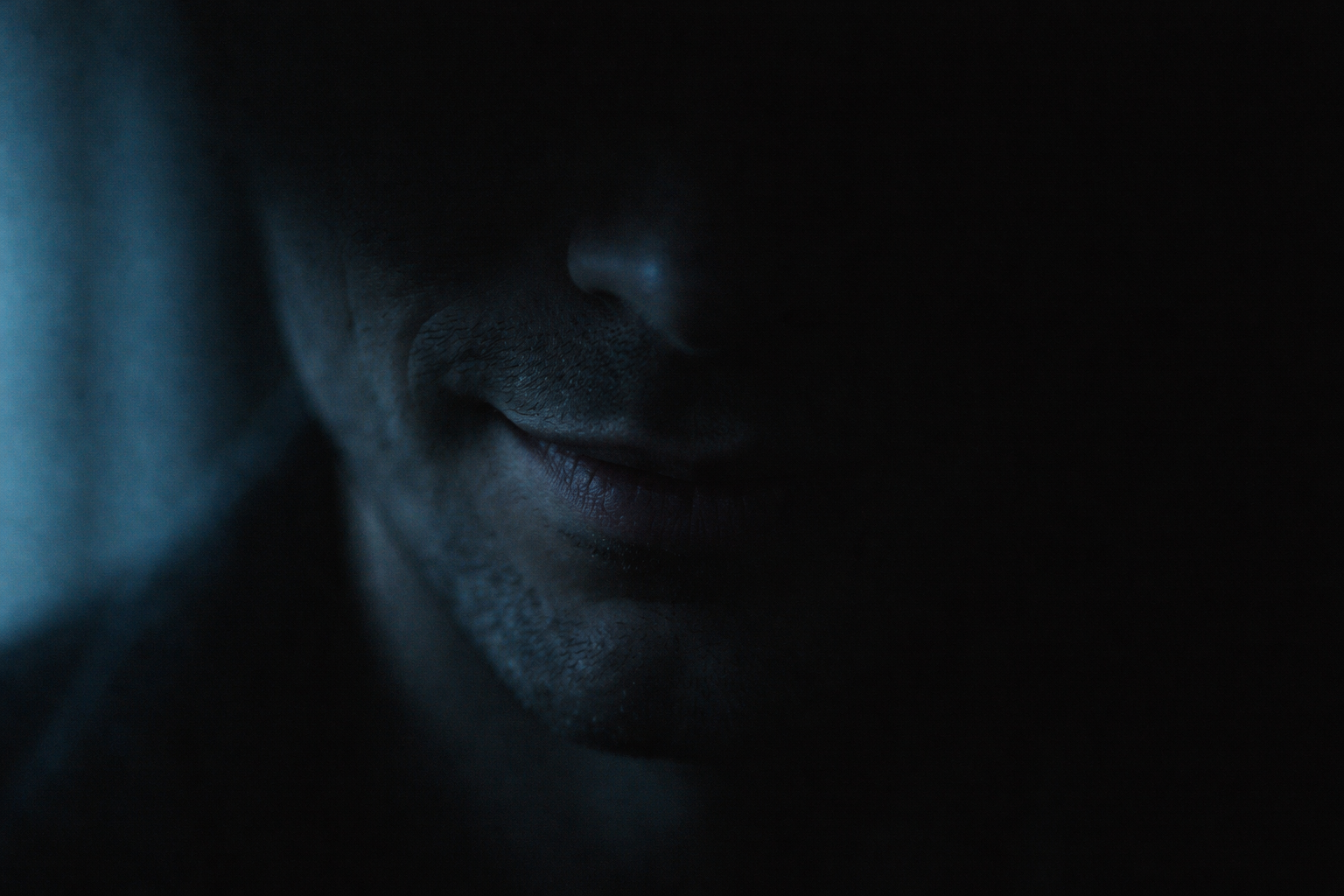 Sinister smirk in shadow